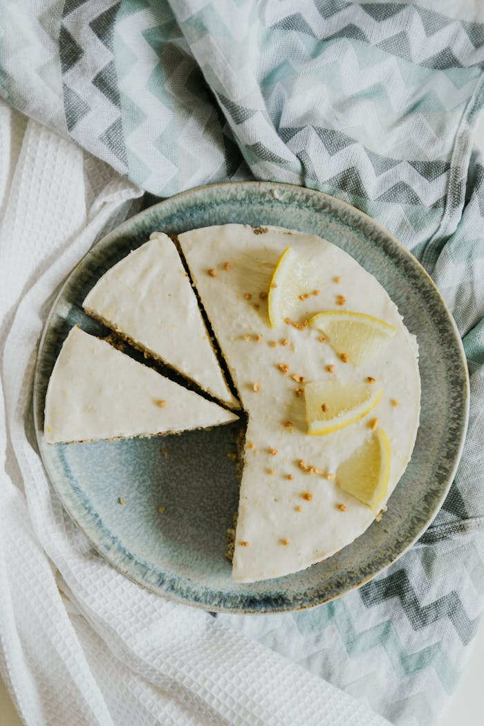 why-choose-us Top view of a creamy lemon cheesecake with slices on a blue plate, perfect for dessert inspiration.
