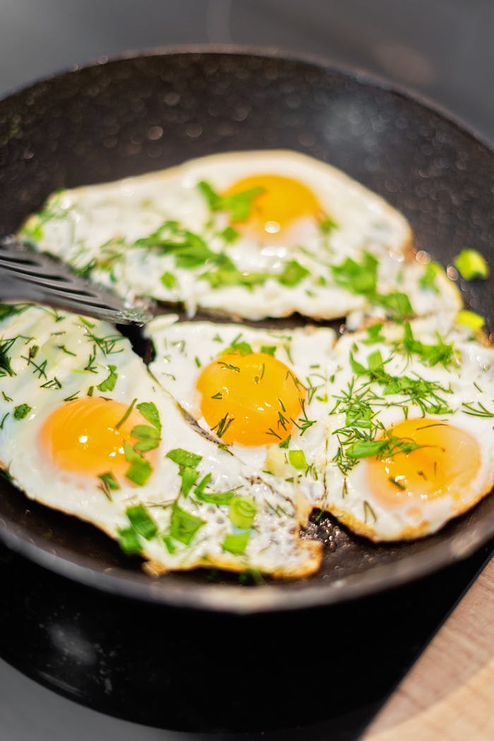 our-services-2 Close-up of fried eggs garnished with herbs, sizzling in a black frying pan. Perfect breakfast inspiration.